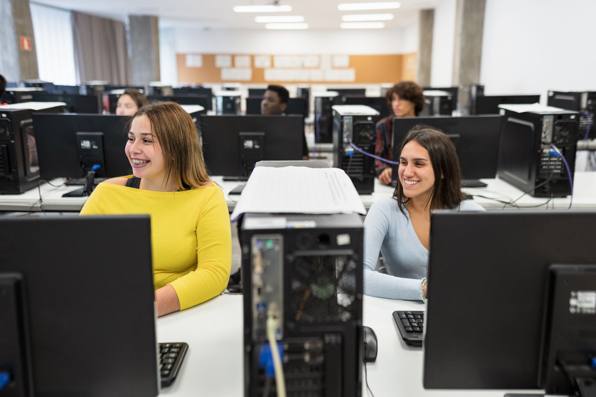 a group of women are sitting in front of computer monitors in a computer lab | Apple Security Solutions