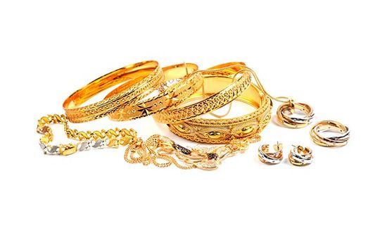 parure di bracciali, anelli, orecchini di oro bianco e oro giallo appoggiati su uno sfondo bianco 