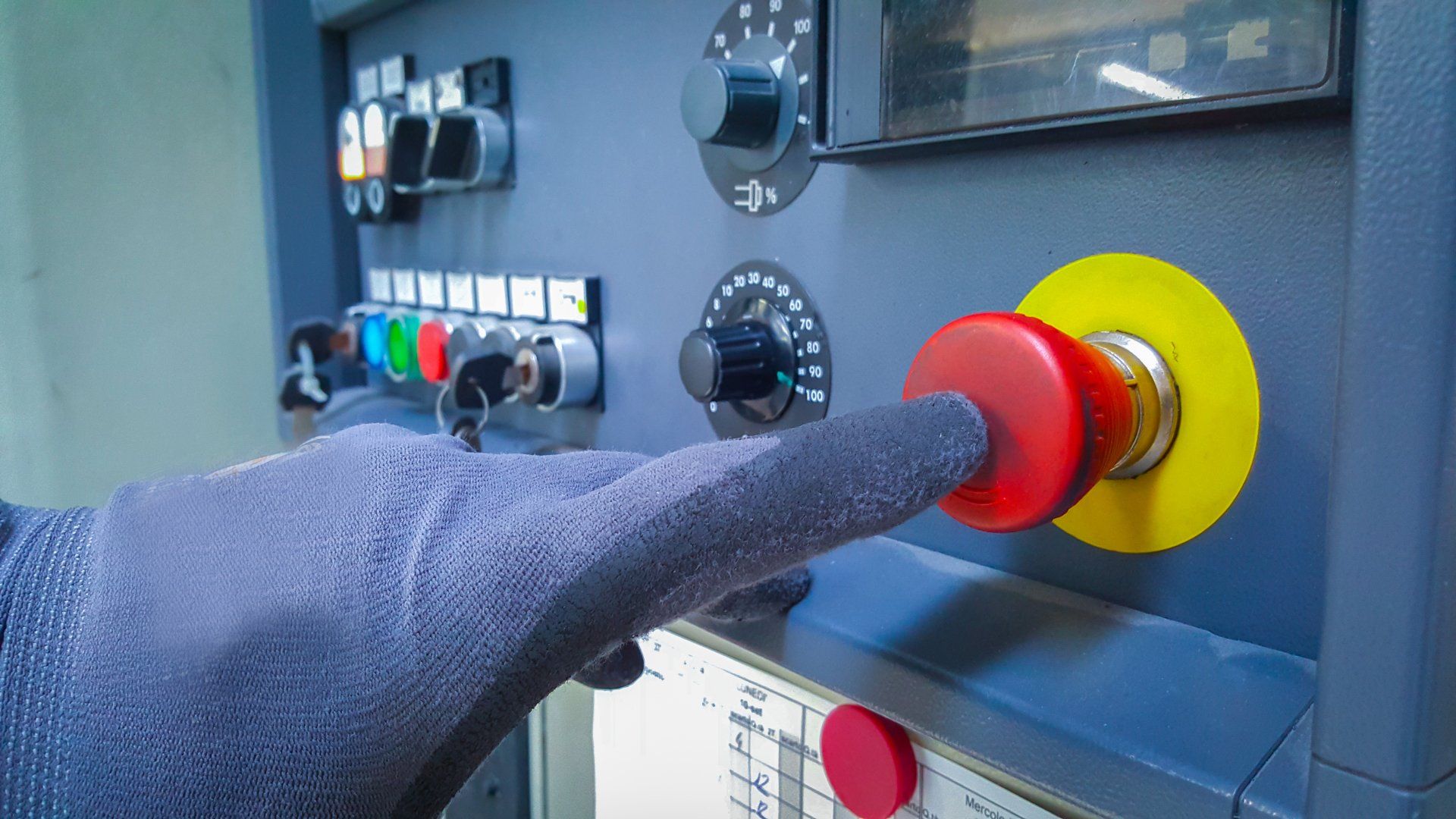 Eine Person drückt einen roten Knopf an einer Maschine.