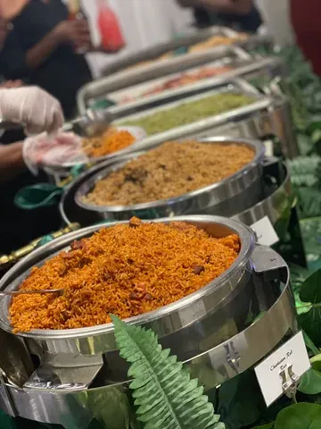 A buffet table laden with various dishes in silver chafing dishes, including orange rice and other food items.