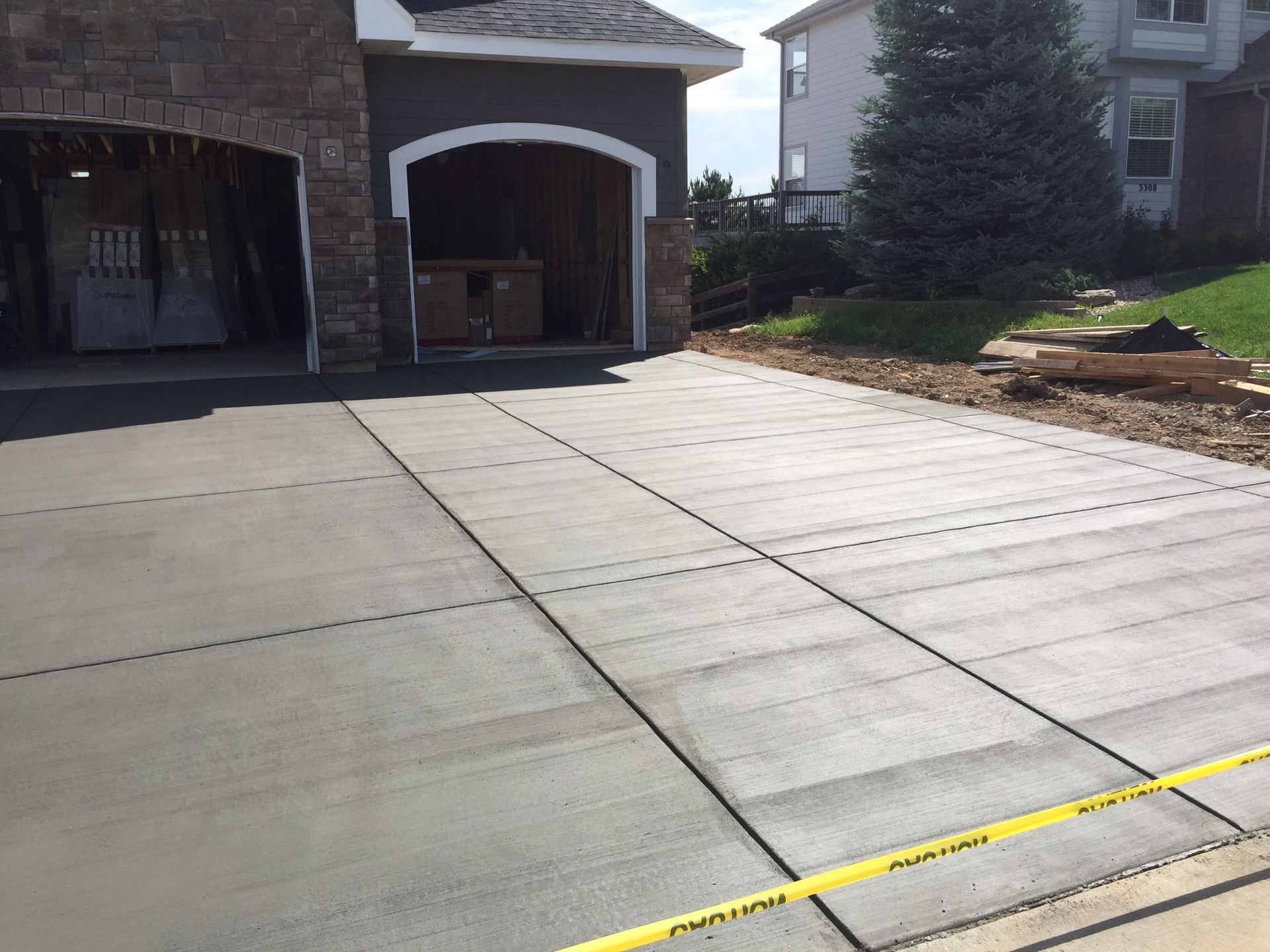 Worker smoothing wet concrete sidewalk with a tool, outdoors.