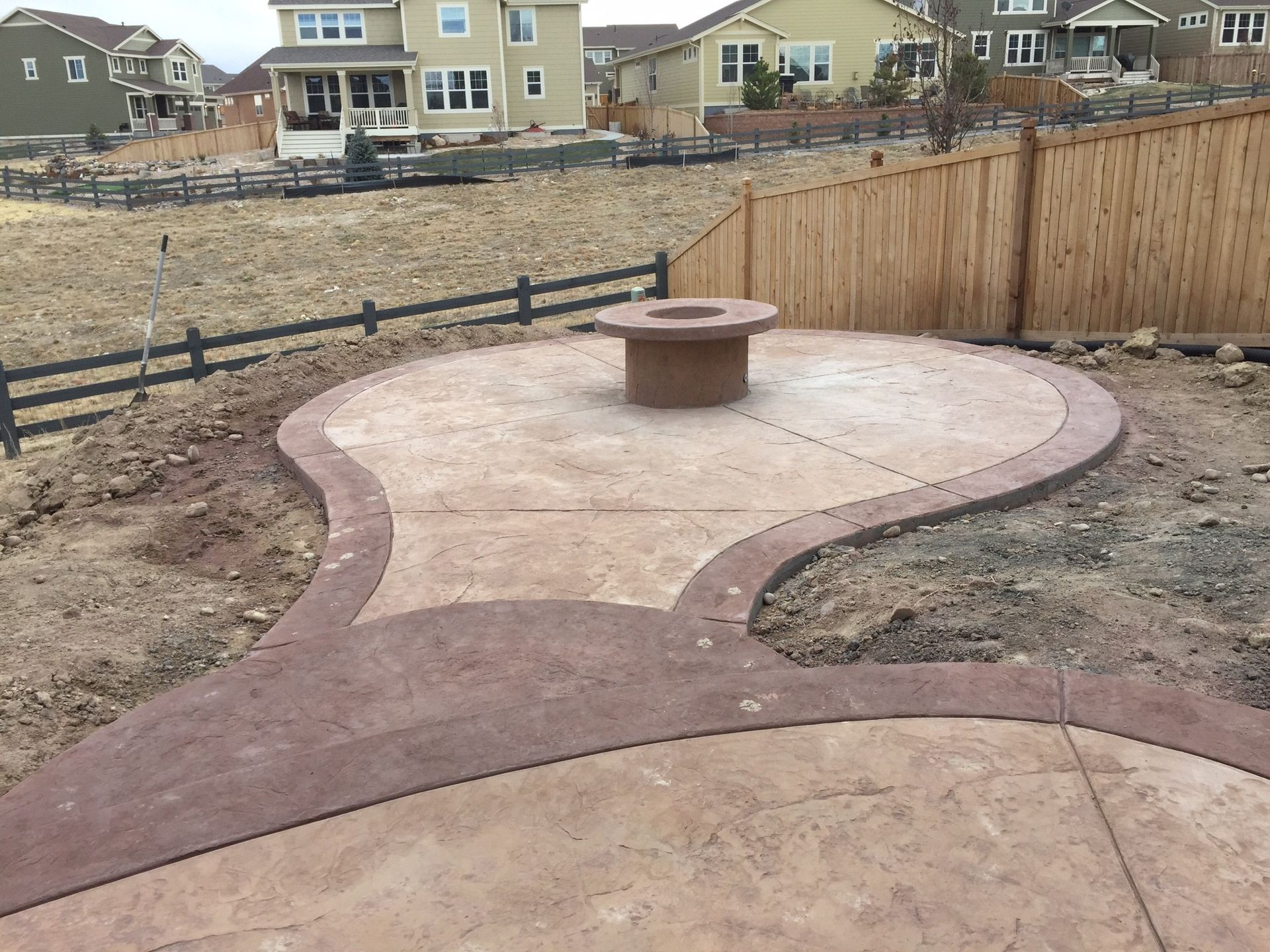 Patio with fire pit, surrounded by Adirondack chairs, brick pavers, and green turf.