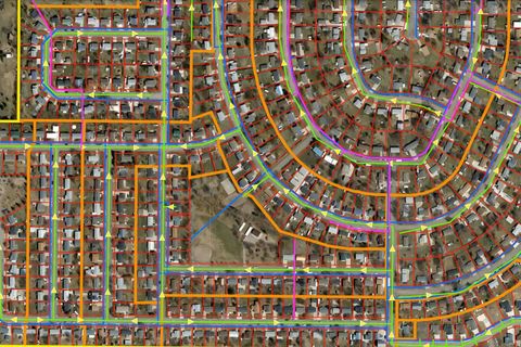 Aerial view of a suburban neighborhood with colorful lines overlaying streets, possibly showing utility lines or data.