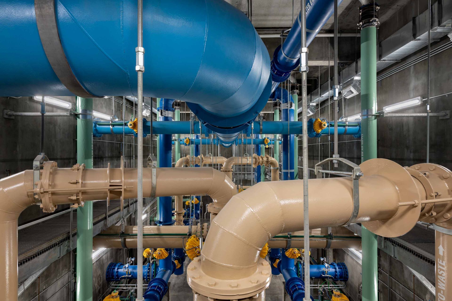 Complex water pipes in various colors inside a utility room.