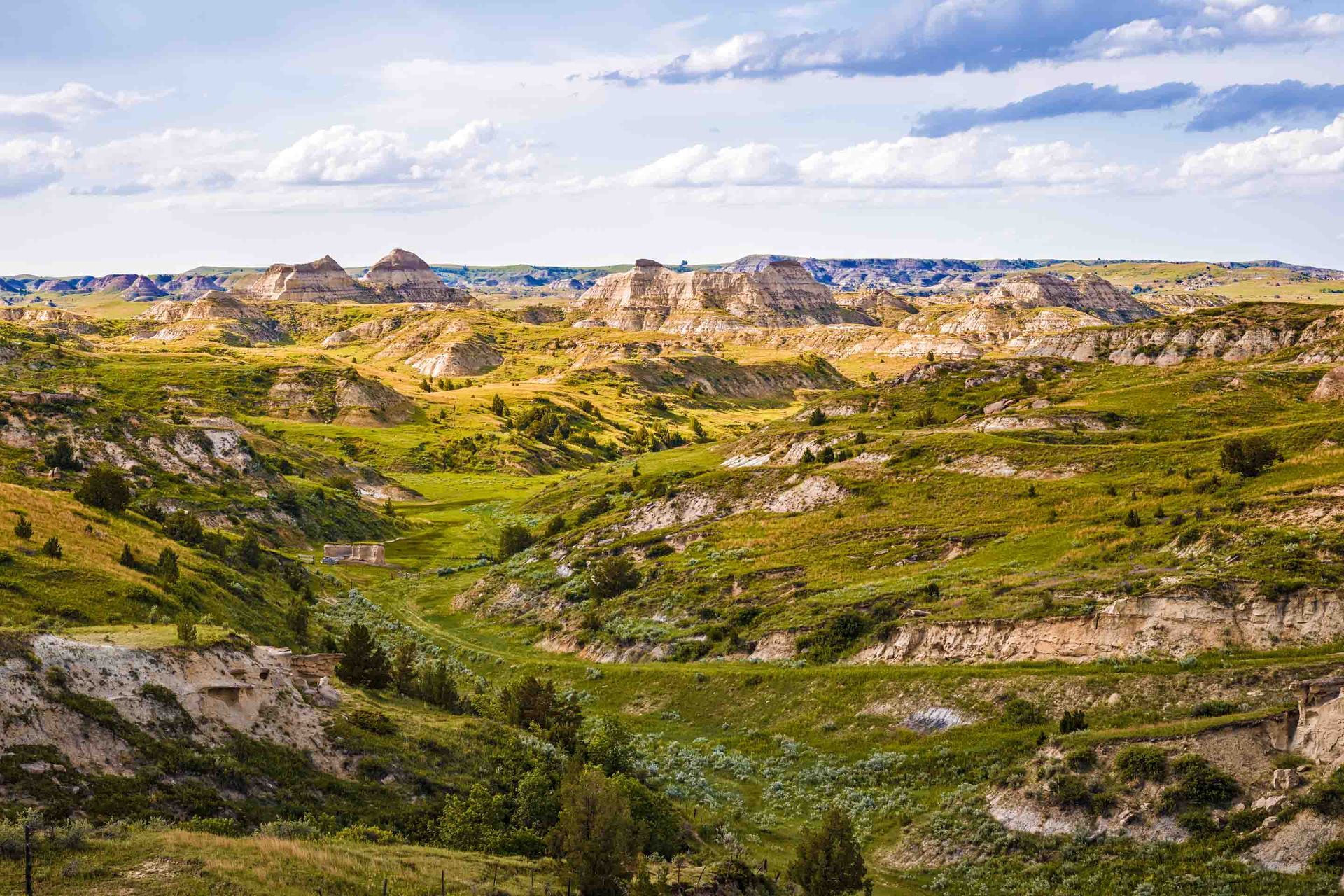 Badlands National Park in South Dakota, scenic view of eroded rock formations and grassy canyons under a blue sky.