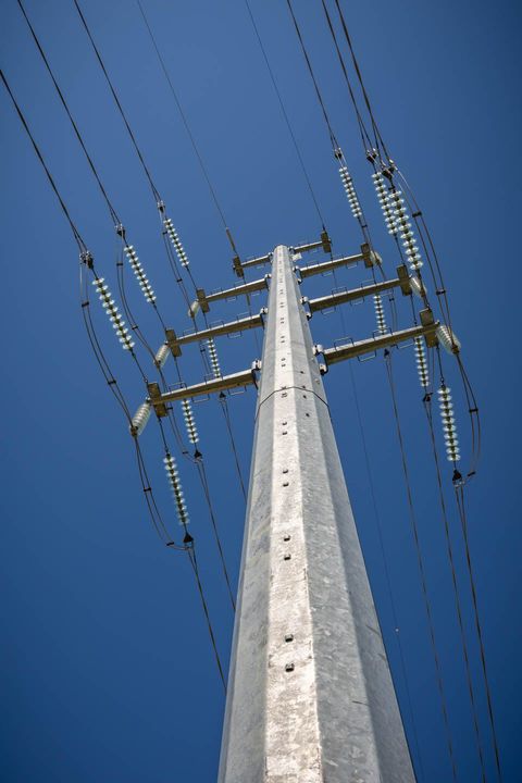 Steel electrical power pylon against a bright blue sky, supporting multiple high-voltage power lines.