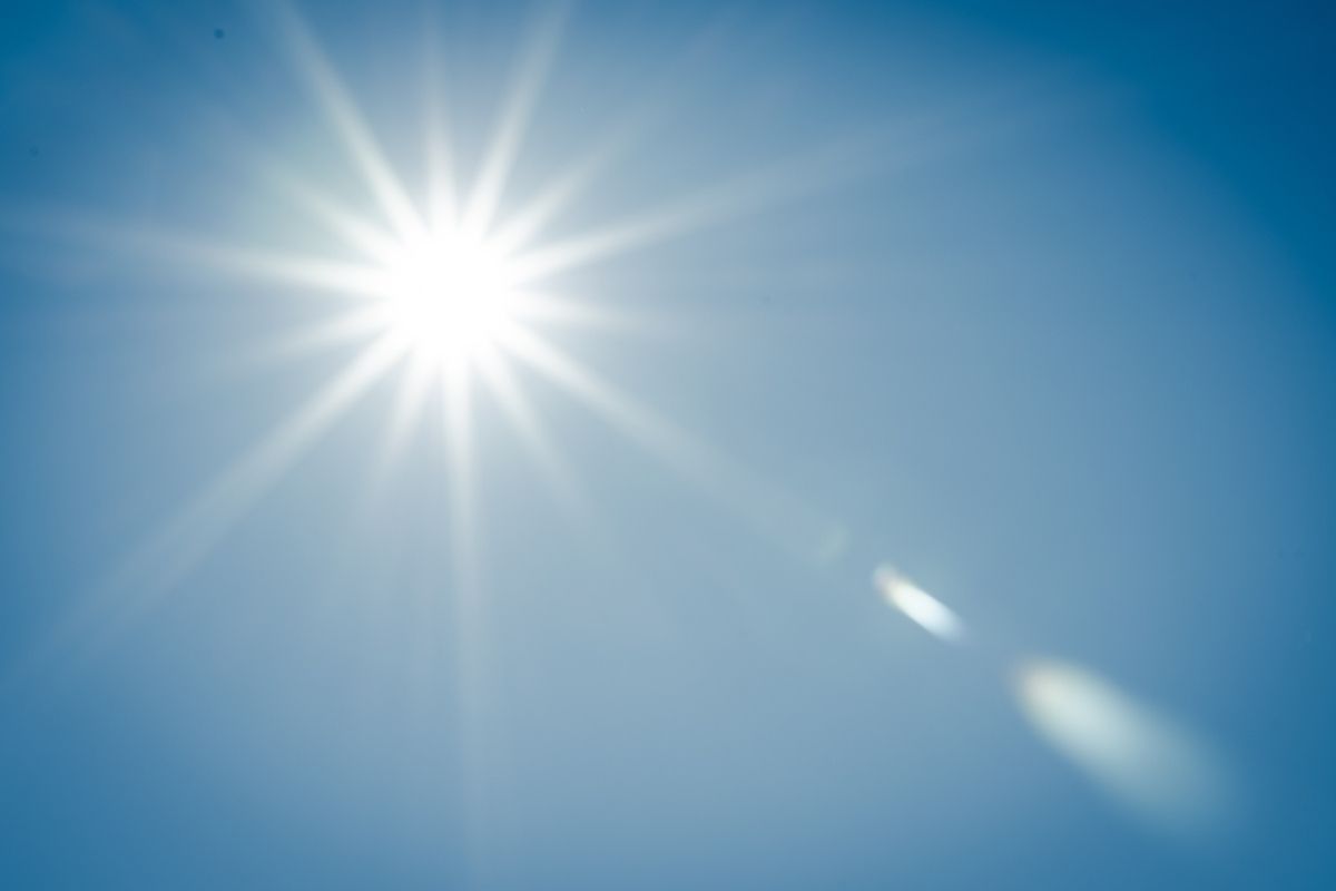 The sun radiates against a clear blue sky, with visible rays and lens flare in Gilbert, AZ