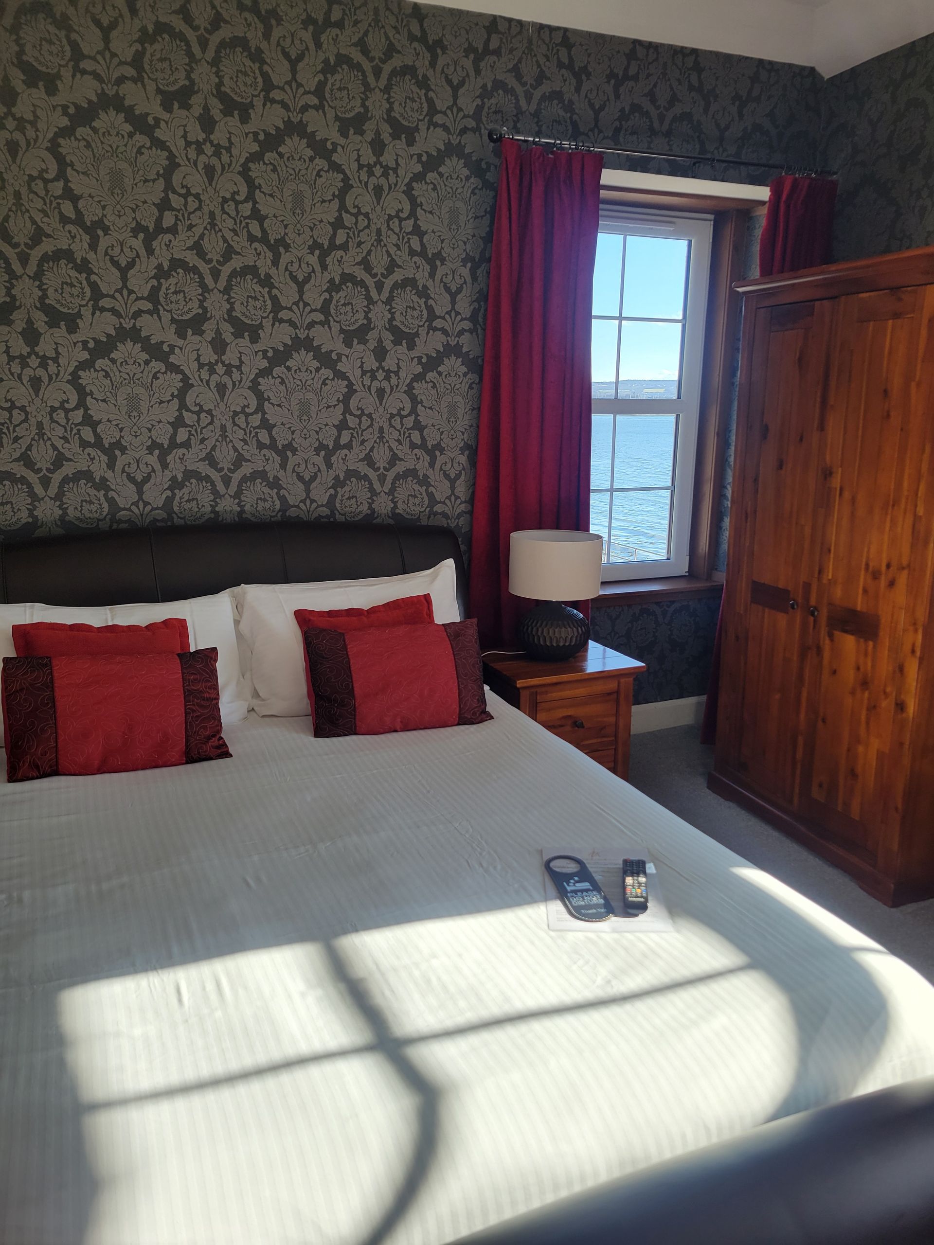 A bedroom with a king size bed , two chairs , and a window.