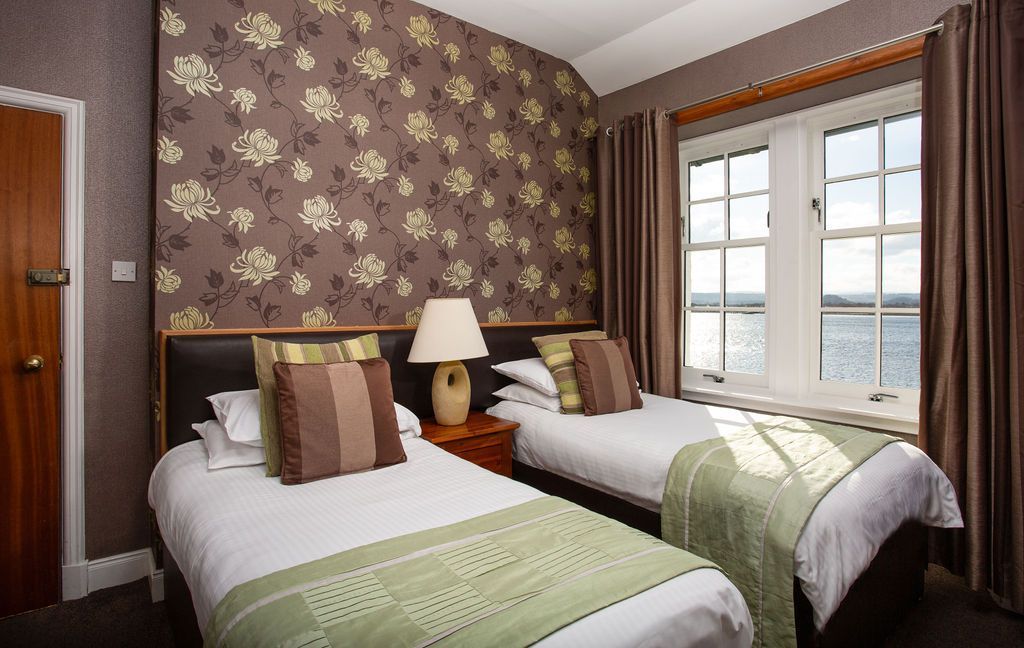 A hotel room with two beds and a large window