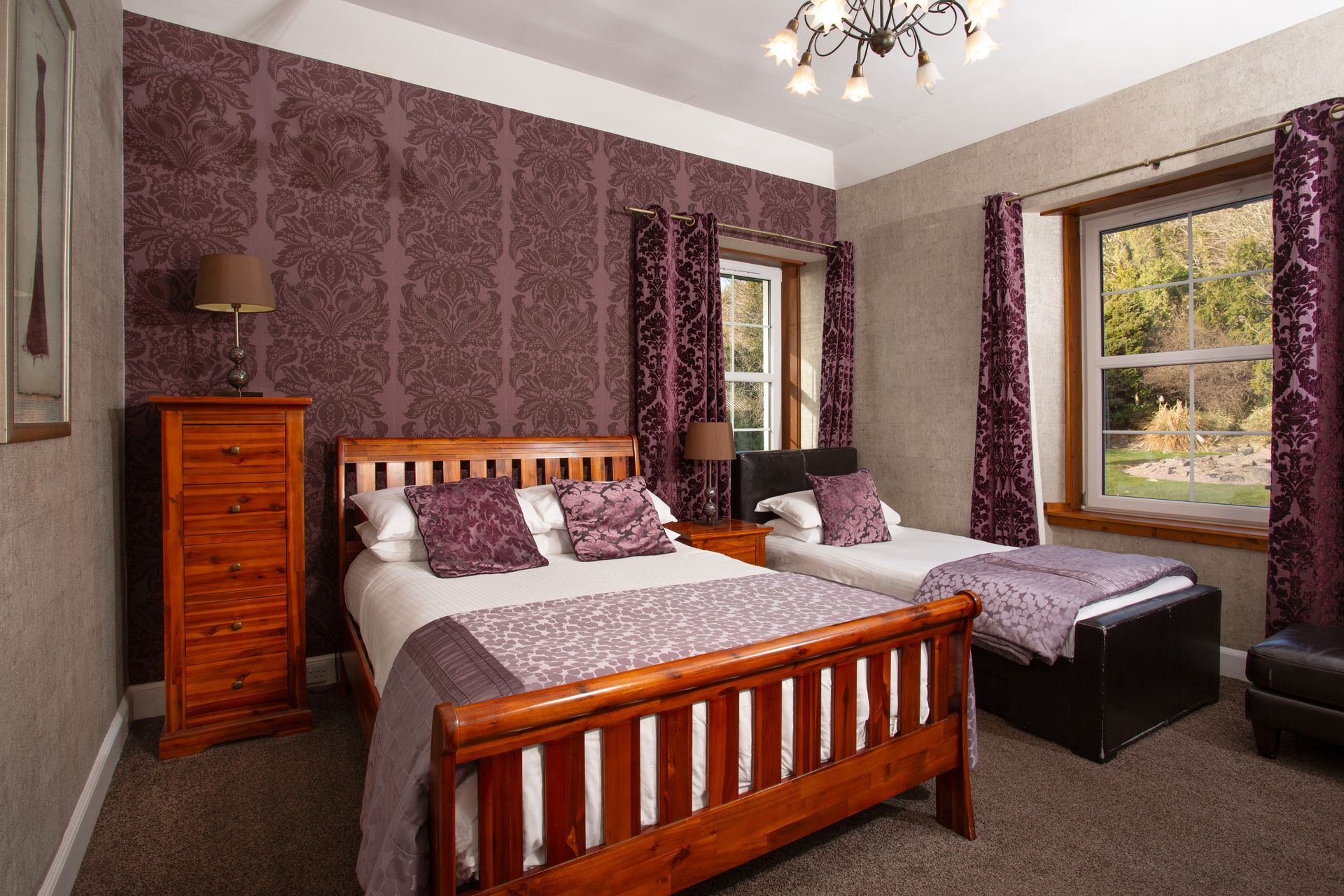 A bedroom with two beds , a dresser , and a window.