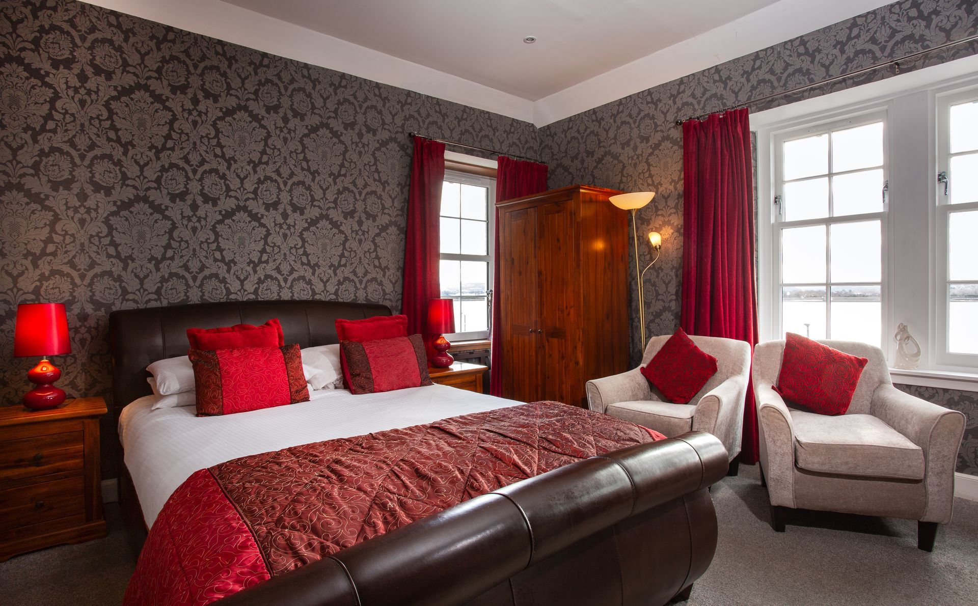 A bedroom with a king size bed , two chairs , and a window.