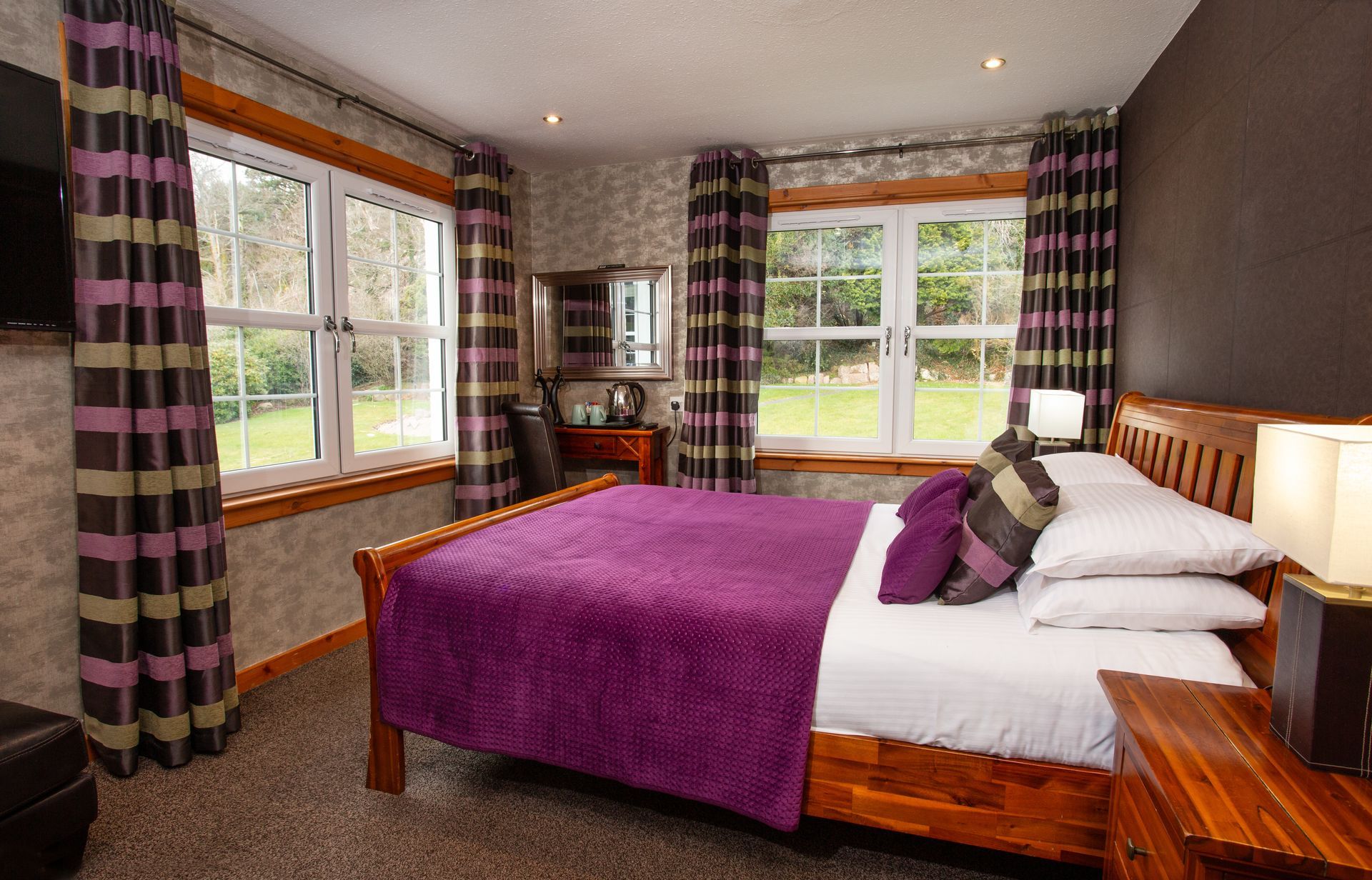 A bedroom with a large bed and purple curtains