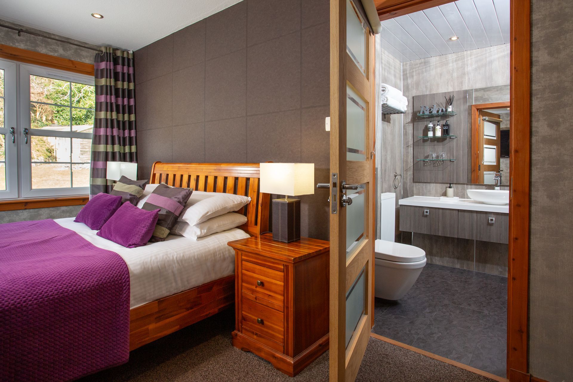 A bedroom with a large bed and a bathroom with a toilet.