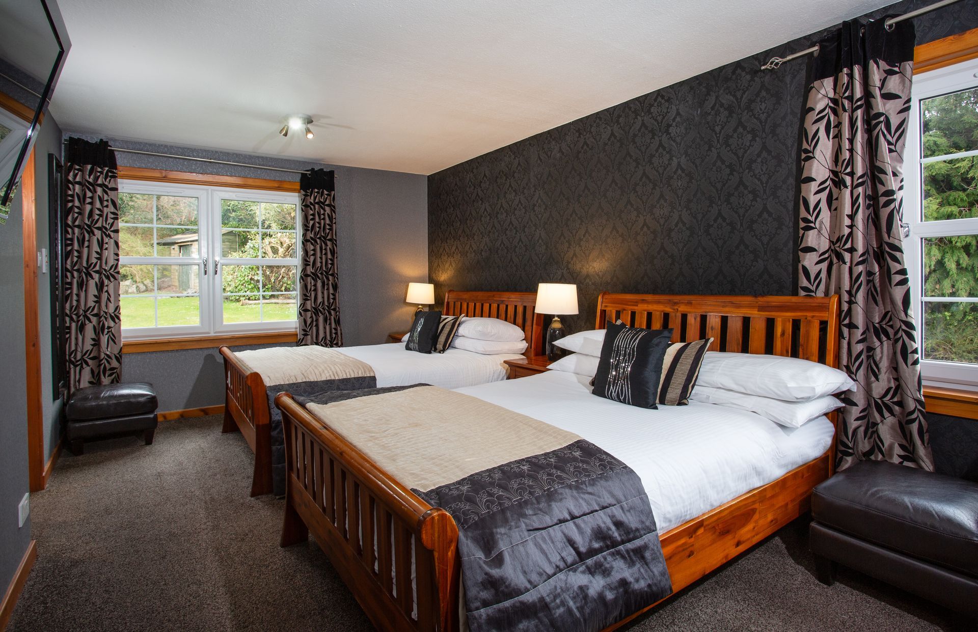 A hotel room with three beds and a television