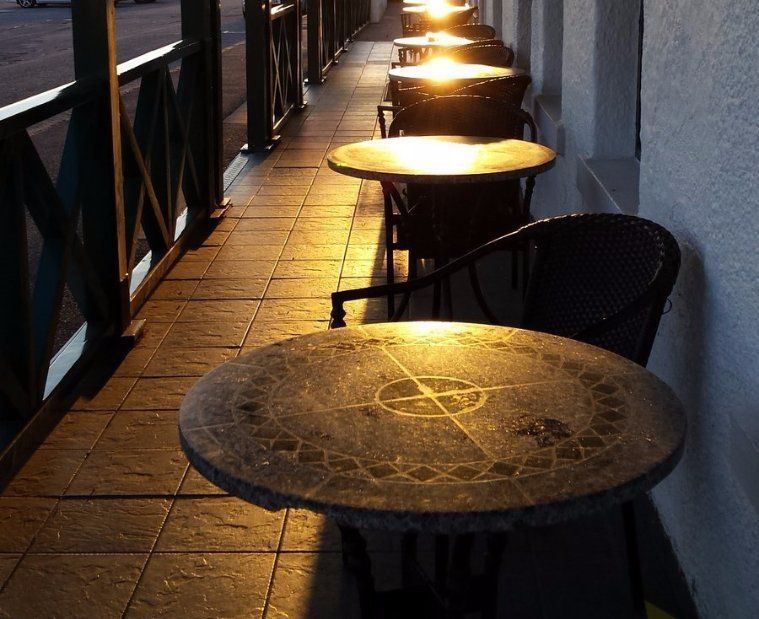 A row of tables and chairs on a sidewalk