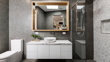 Modern gray bathroom with floating vanity, round sink, and large mirror.