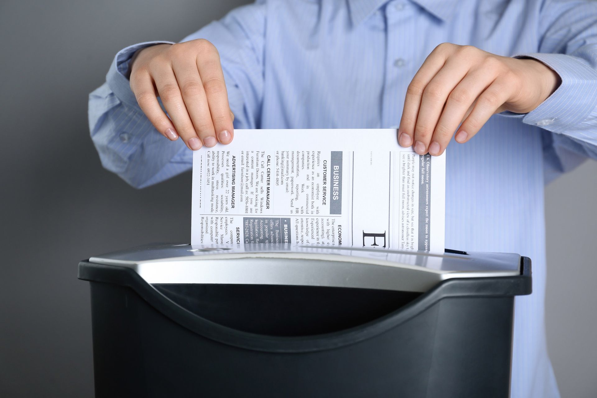 A man is shredding a piece of paper in a paper shredder.