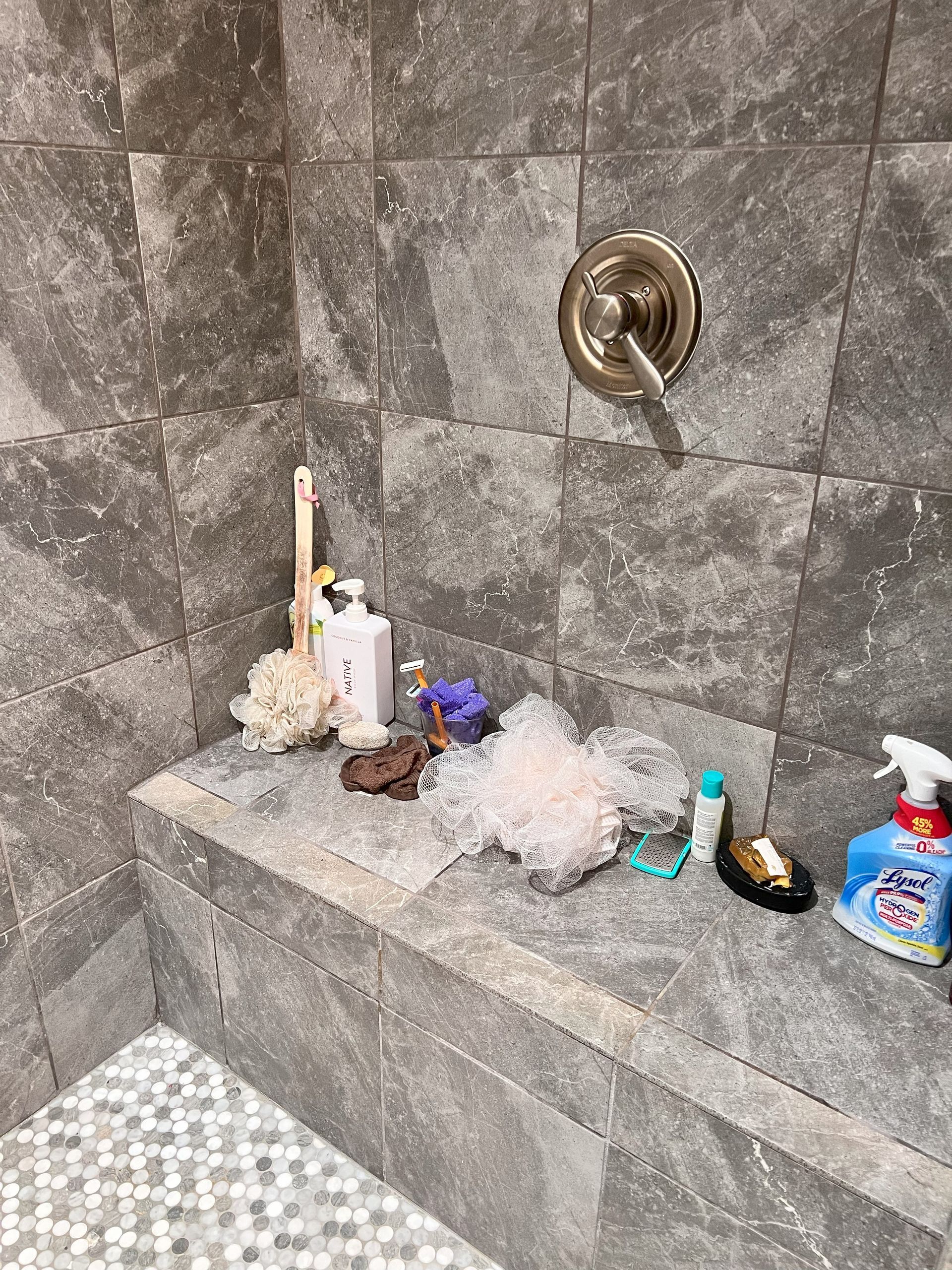 A shower stall with a shelf filled with toiletries and a shower head.