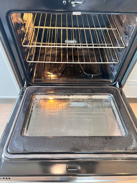 The inside of a dirty oven with the door open.