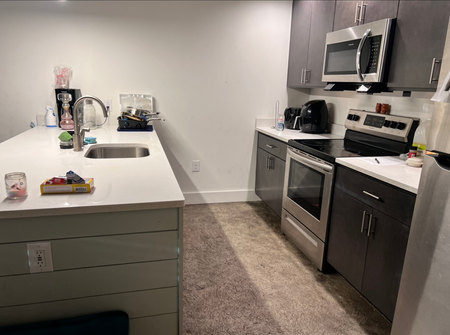 A kitchen with a sink , stove , microwave and refrigerator.