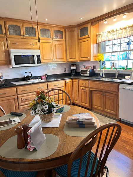 A kitchen with wooden cabinets and a table with a vase of flowers on it.