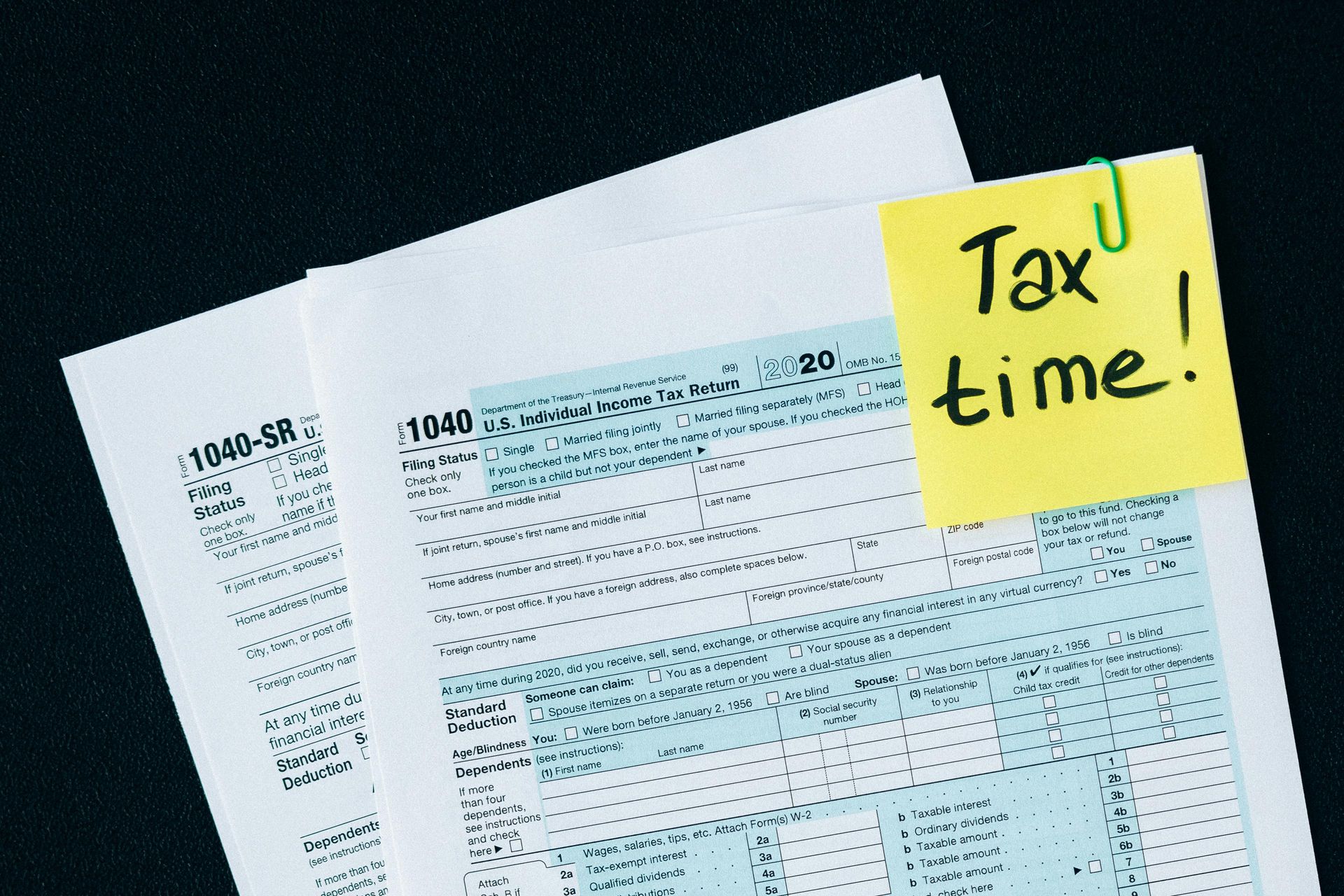 Tax forms with a yellow sticky note reading “Tax time!”