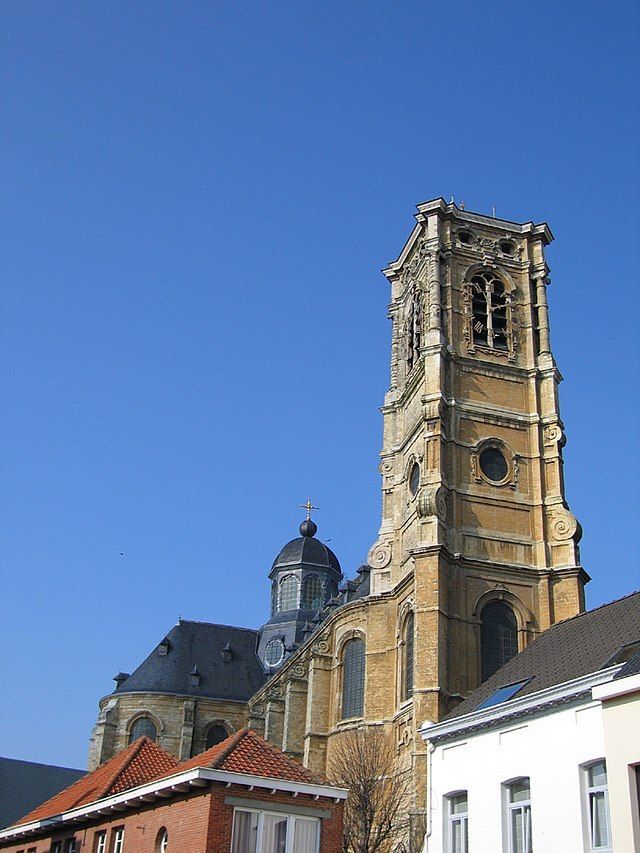 A tall, ornate brick church tower with a blue sky background.