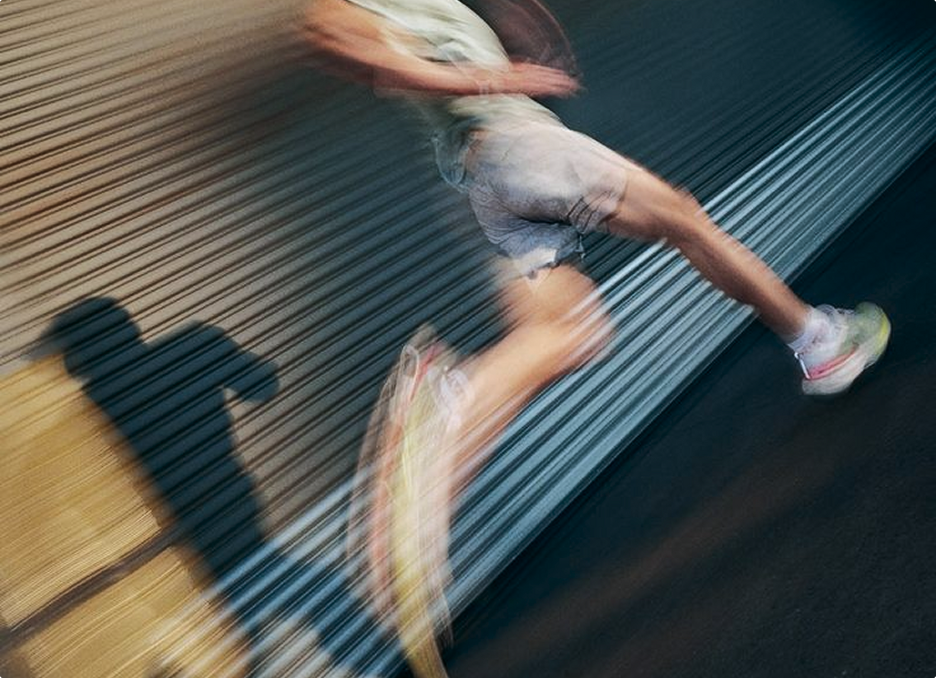Man running with blurred motion in front of a corrugated metal wall.