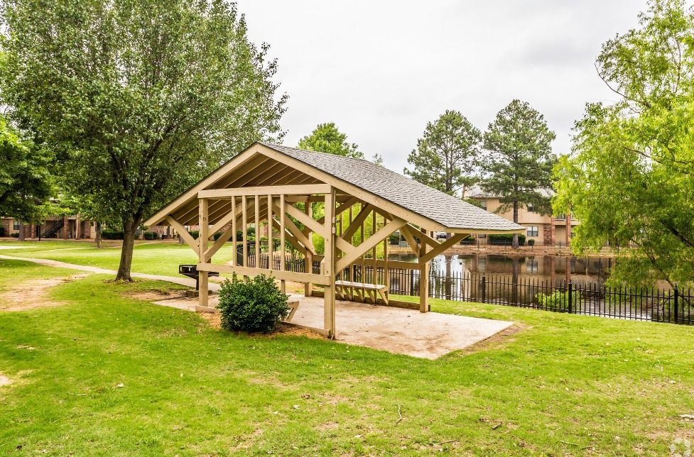 A wooden pavilion is sitting in the middle of a grassy field.
