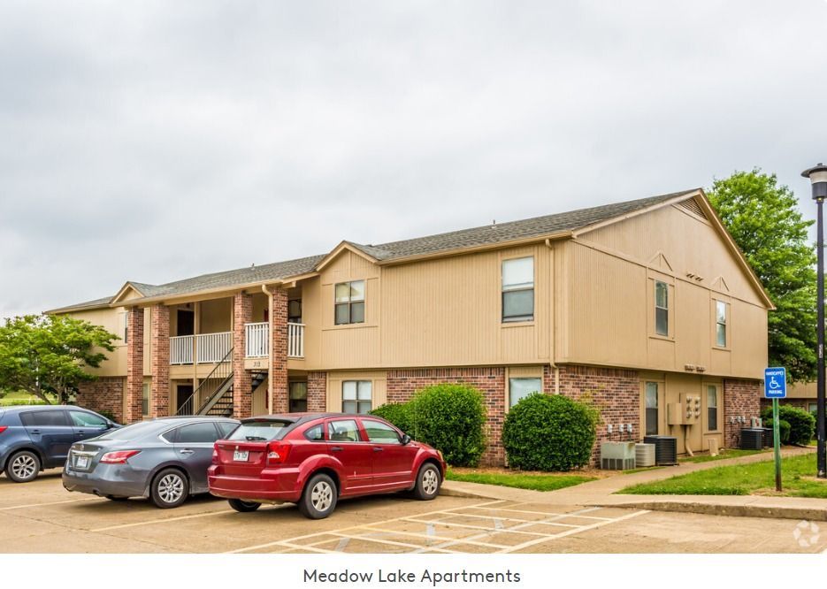 A large apartment building with cars parked in front of it.