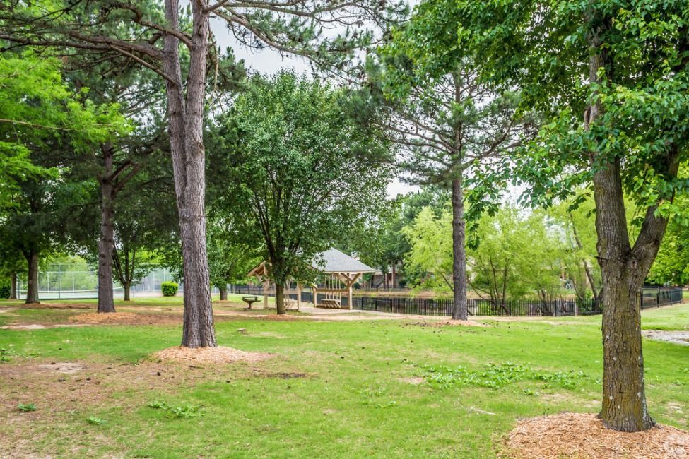 There is a gazebo in the middle of the park surrounded by trees.