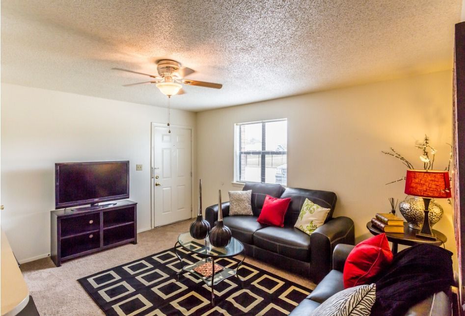 A living room with a couch a television and a ceiling fan