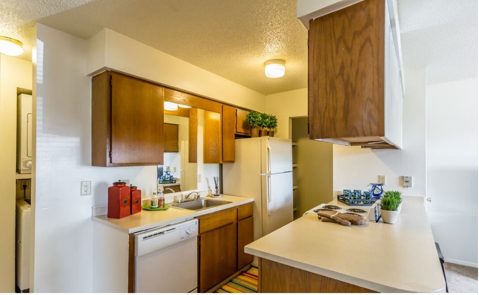 A kitchen with wooden cabinets , white appliances , a refrigerator and a sink.