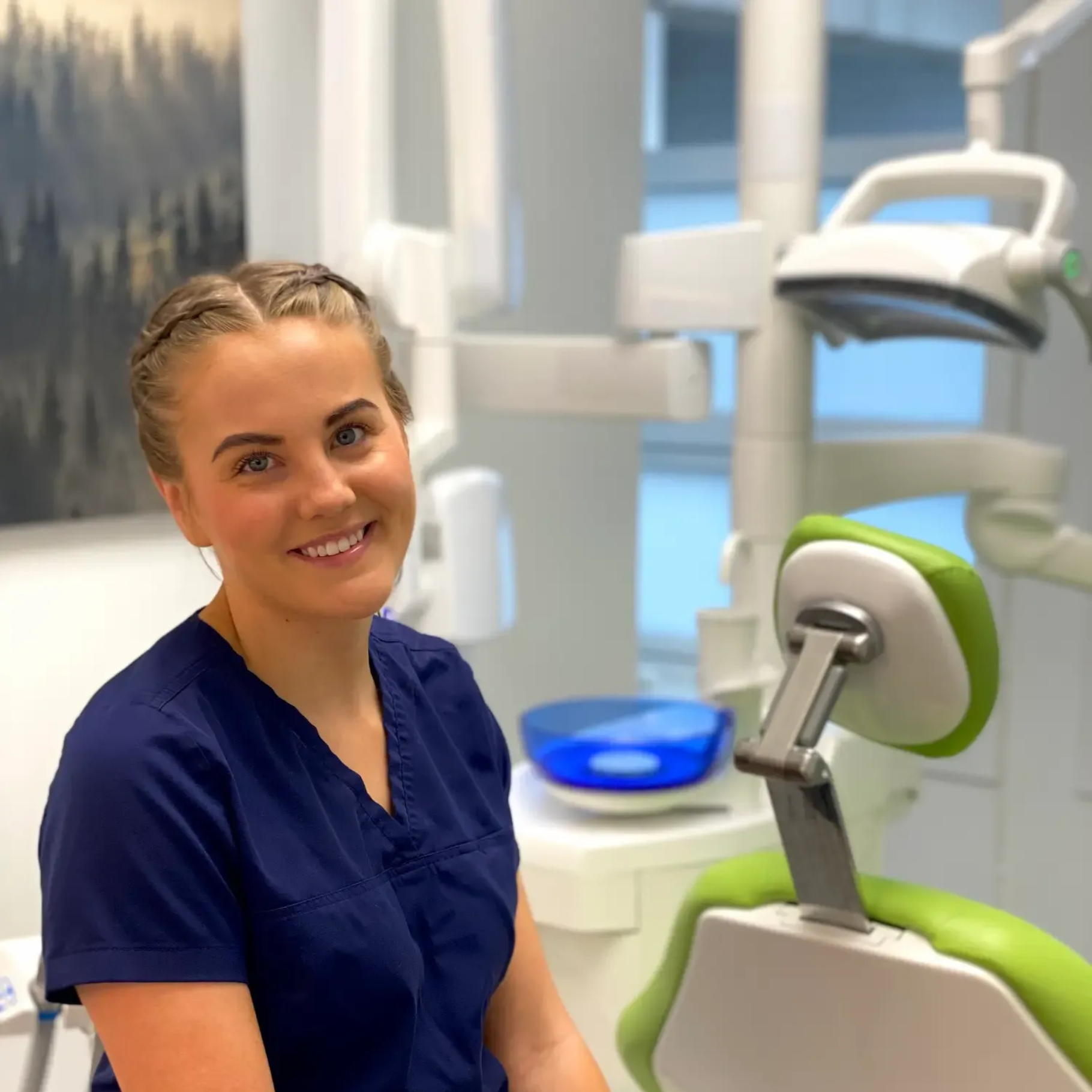 Tannlege Christian med briller og skjegg, iført blå skjorte og medisinsk maske, smiler til kameraet.