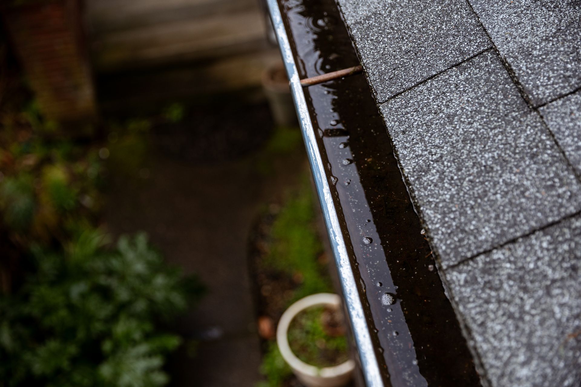 A close-up of a roof gutter during a rainstorm. Shot from above looking down. A close-up of a roof gutter during a rainstorm. Shot from above looking down.