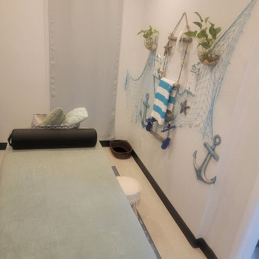 Massage room with nautical-themed decor, including a massage table and decorative wall accents.