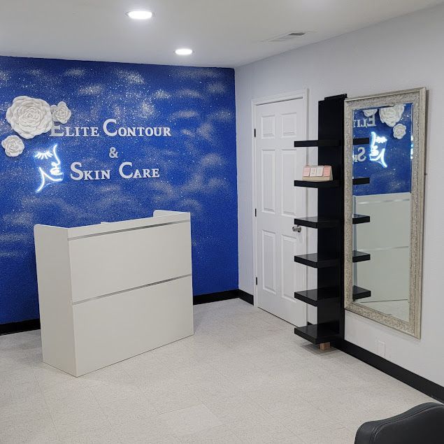 Interior of a skin care business with a white reception desk, blue accent wall, shelves, and a large mirror.