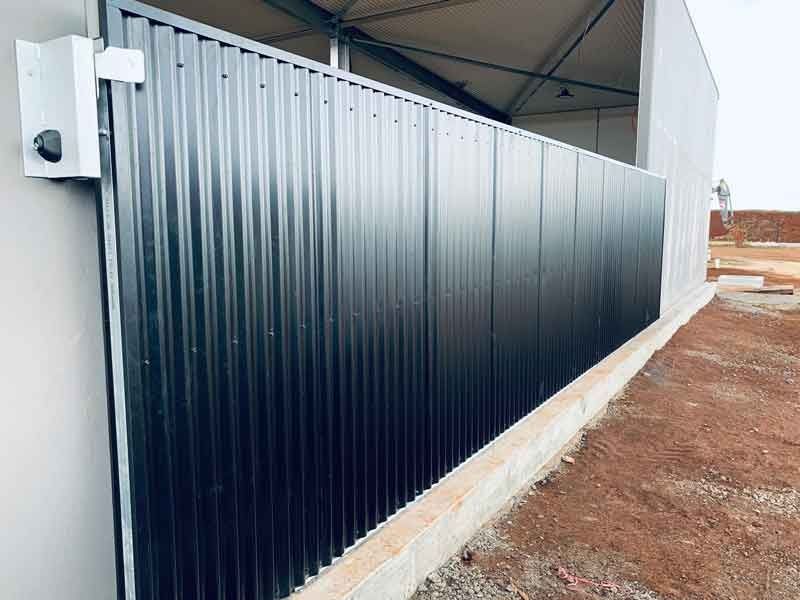 A Black Metal Fence is Sitting Next to a Building — Fencing Around In Mareeba, QLD