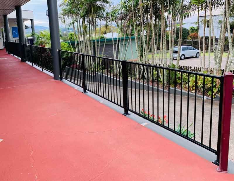A Black Railing Along a Walkway With a Car Parked Behind It — Fencing Around In Mareeba, QLD