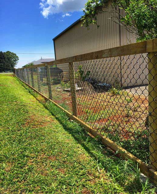 A Chain Link Fence With a Wooden Post in Front of a Building — Fencing Around In Mareeba, QLD
