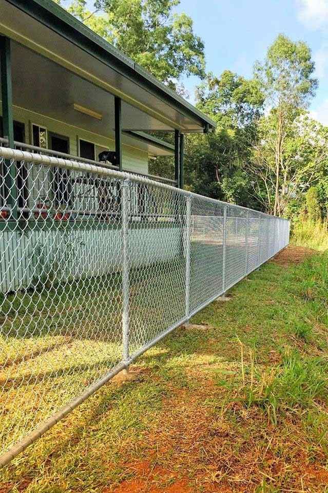 A Chain Link Fence is Surrounding a House in a Grassy Field — Fencing Around In Mareeba, QLD