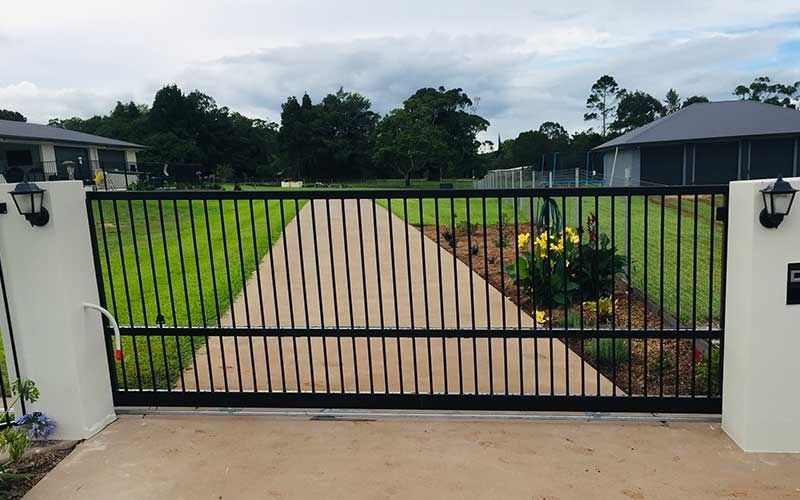A Black Sliding Gate is Open to a Driveway Leading to a House — Fencing Around In Mareeba, QLD
