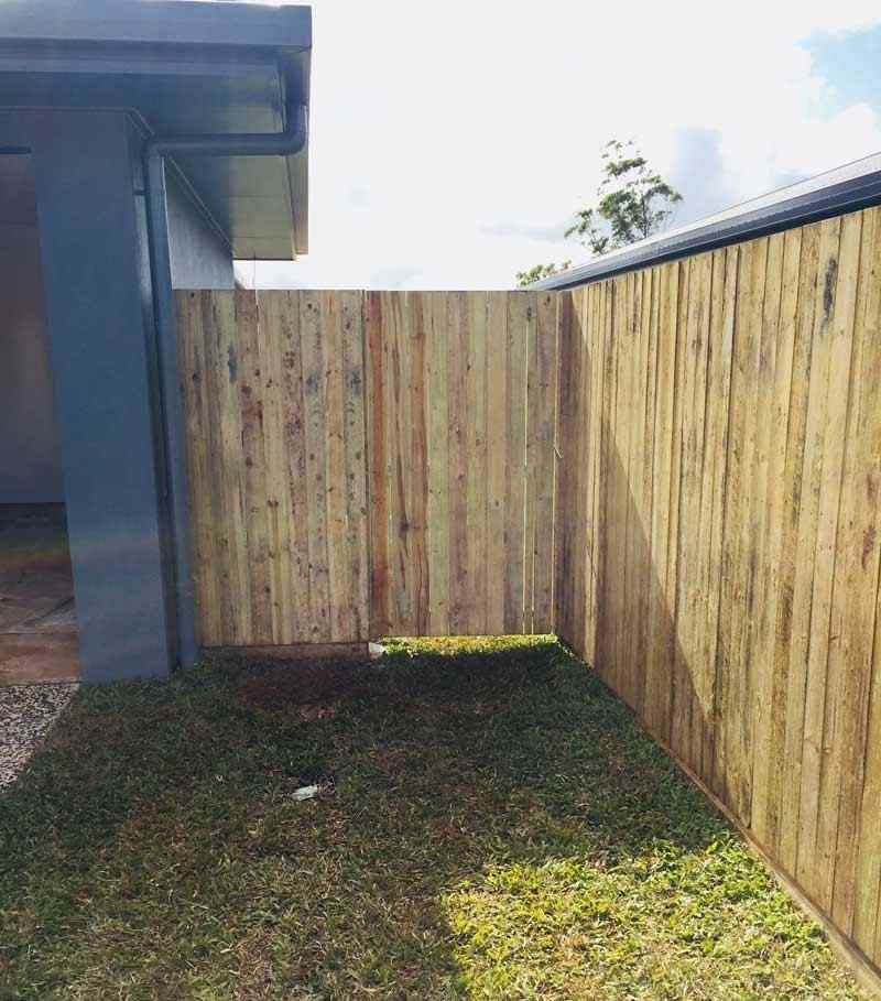 A Wooden Fence Surrounds a Lush Green Yard Next to a House — Fencing Around In Mareeba, QLD