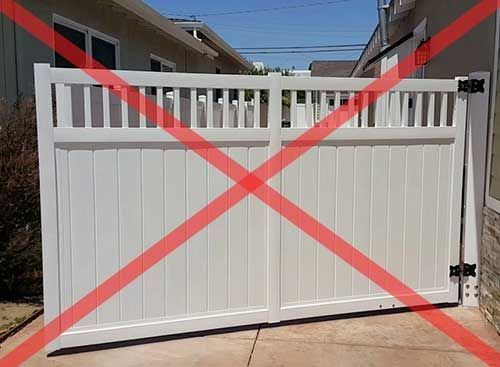 A White Gate With a Red Cross Through It is Sitting in Front of a House — Fencing Around In Mareeba, QLD