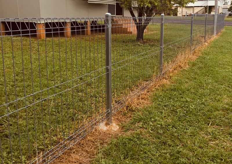 A Wire Fence Surrounds a Lush Green Field in Front of a House — Fencing Around In Mareeba, QLD