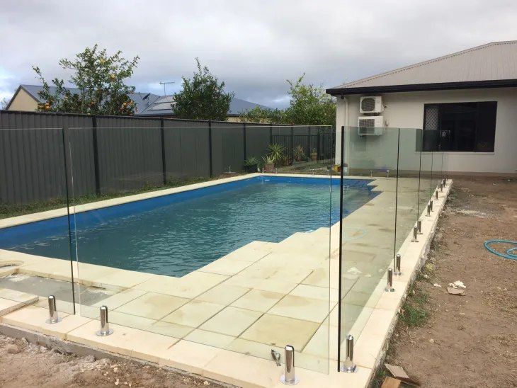 A Large Swimming Pool is Surrounded by a Glass Fence — Fencing Around In Mareeba, QLD