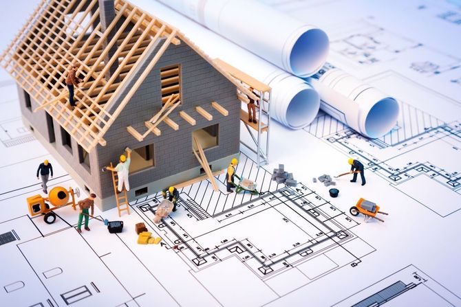 Modello architettonico di una casa in costruzione, realizzato su planimetrie, con operai e progetti nelle vicinanze.
