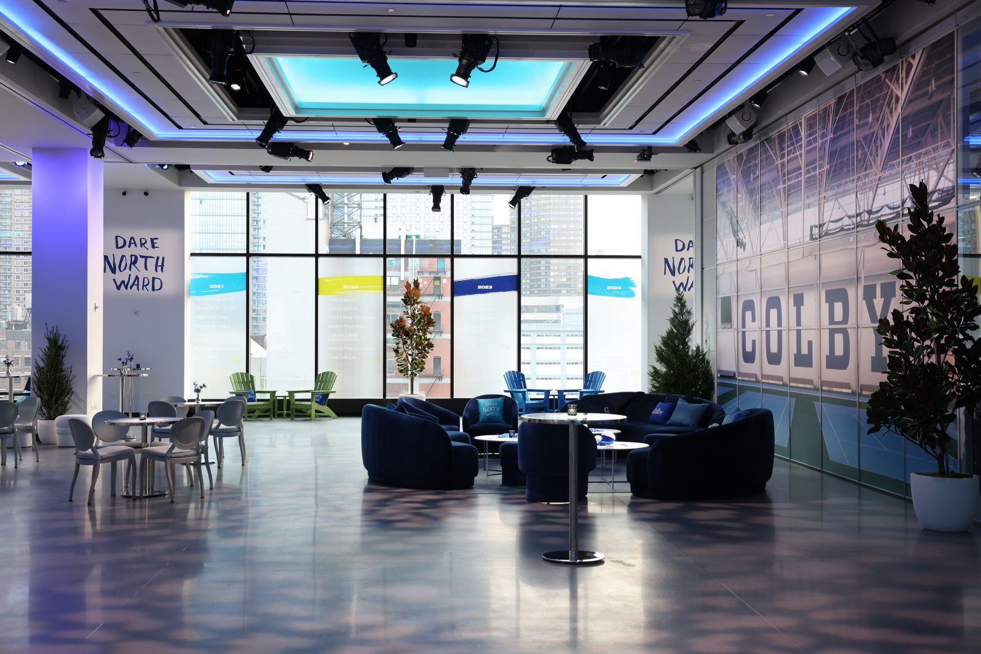 Modern interior with blue couches, tables, and large windows overlooking a city.