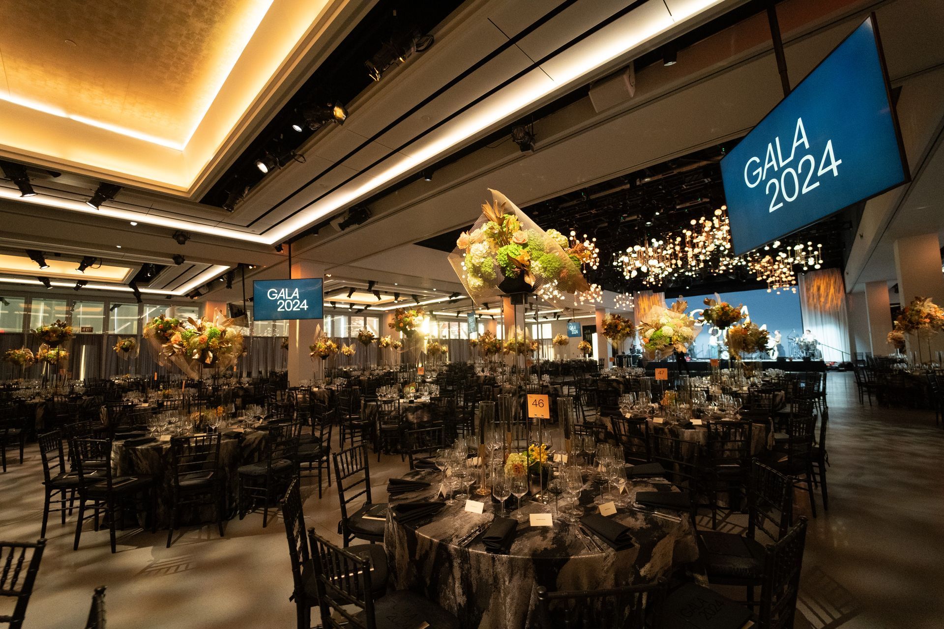 A large room with tables and chairs and a sign that says gala 2024