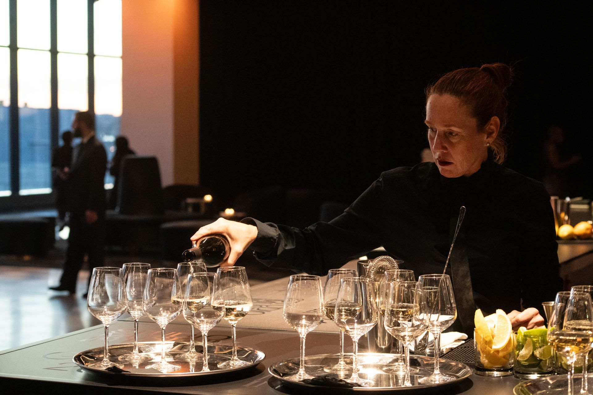 A woman is pouring wine into a glass on a table.
